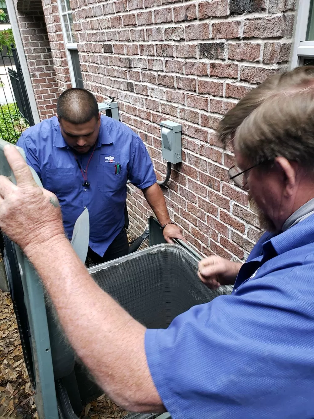 Two Texas Ace Heating & Air technicians working on a HVAC system